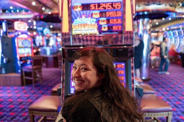 Mujer disfrutando de jugar en una maquinita tragamonedas física en casino